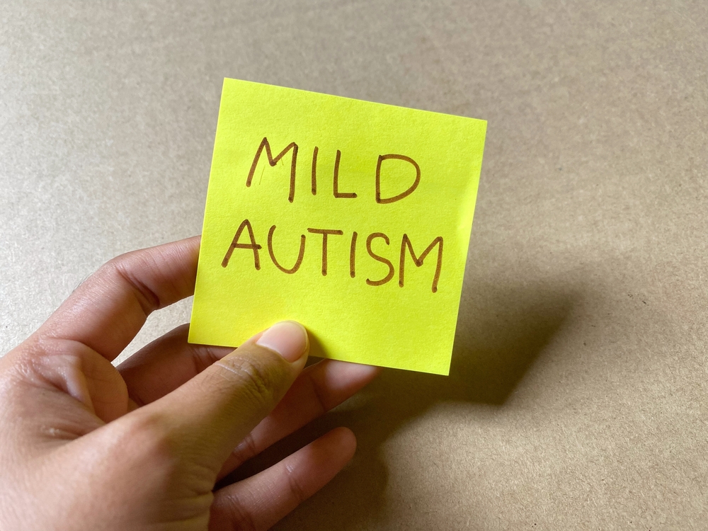A neon green sticky note with the words “mild autism” written on it.
