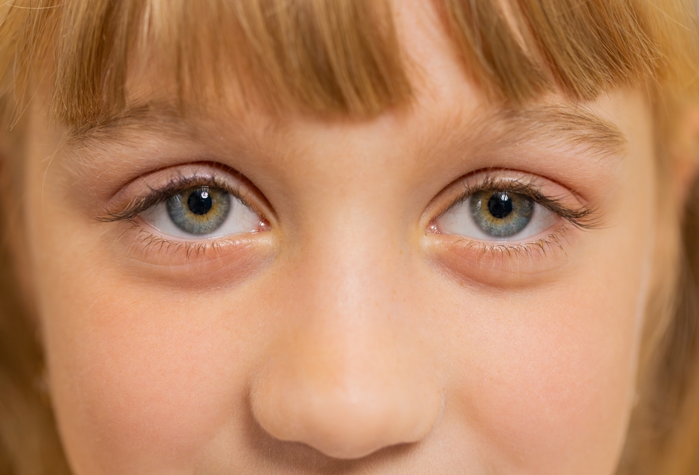 Extreme close-up of a young blond-haired girl's blue eyes and long eyelashes.
