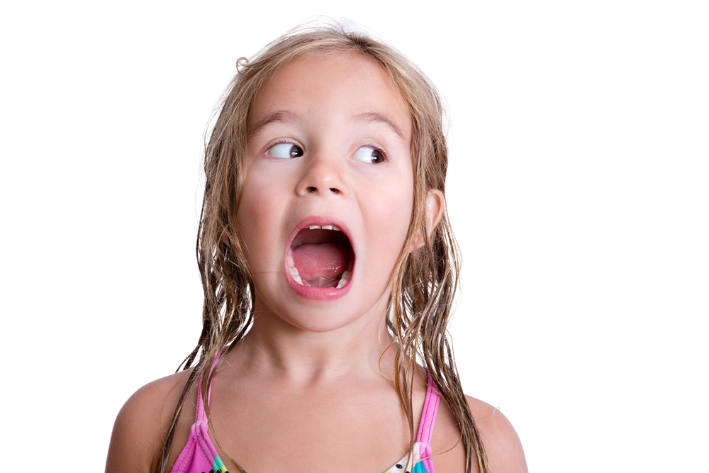 A young brown-haired girl in a bathing suit with her mouth wide open as she looks to her left.
