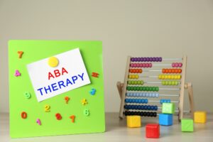 ABA therapy tools for children including a colorful abacus, numbered building blocks, and a magnetic board labeled "ABA Therapy."