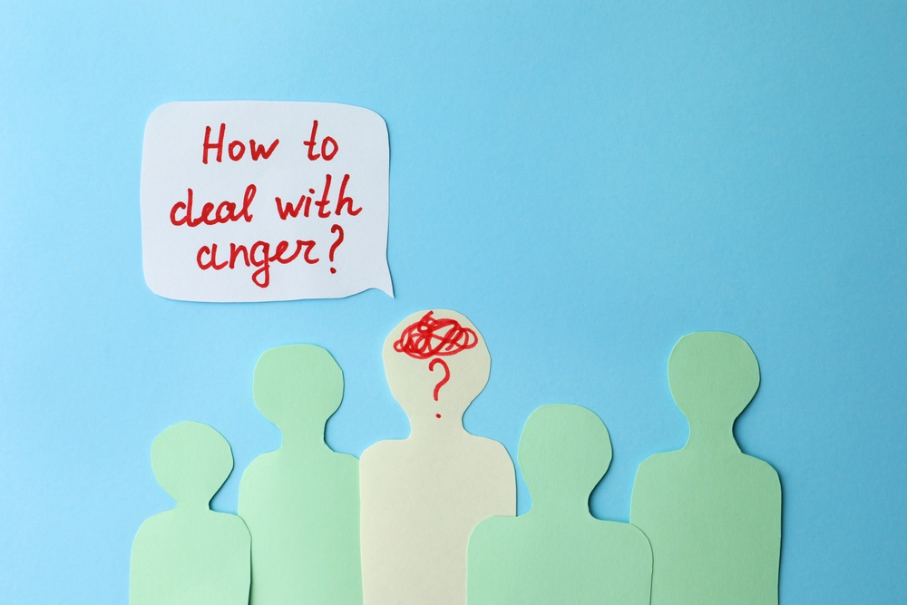 Paper cutout figures on a blue background, with one highlighted figure showing a red scribble and question mark inside its head, and a speech bubble asking "How to deal with anger?