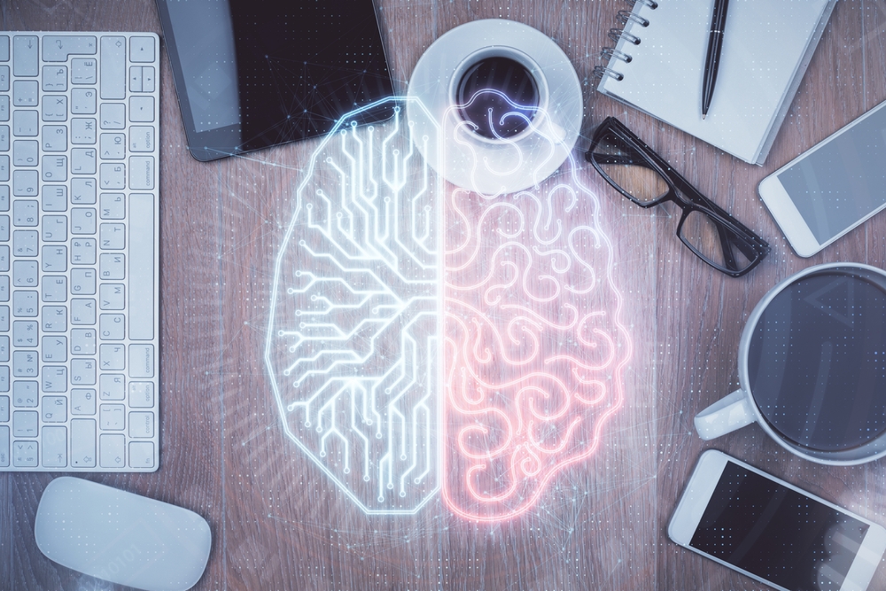 Digital illustration of a split brain graphic overlaid on a desk with a keyboard, glasses, coffee, and smartphones — one half showing circuit-board patterns, the other showing organic neural pathways. 