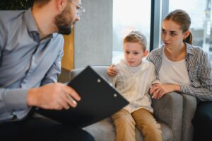 Therapist reviewing notes with a young child and parent during a consultation