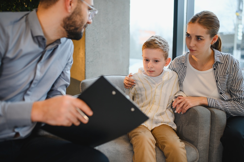 Therapist reviewing notes with a young child and parent during a consultation