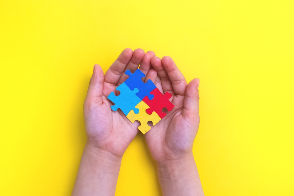 Small hands playing with multicolored jigsaw pieces
