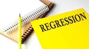 The word “regression” written in all caps on a bright yellow card with a pencil next to it.