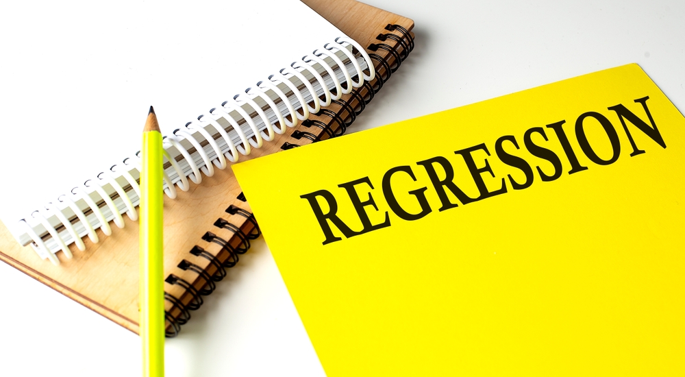 The word “regression” written in all caps on a bright yellow card with a pencil next to it.
