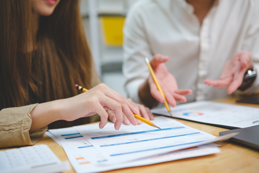 A man and a woman reviewing automated results on paper using pencils